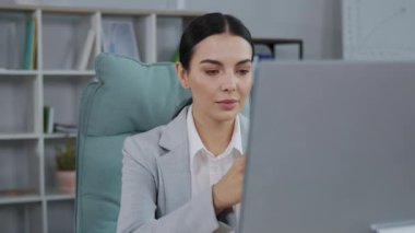 İş kadını ofiste otururken korkunç haberlerden korkarak bilgisayar ekranına bakıyor. Korkmuş kadın portresi, kötü haberlere tepki, ofiste oturmak..