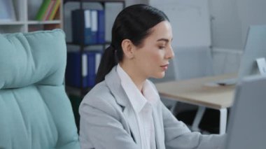 Güzel görünümlü, at kuyruklu genç bir kadının rahat ofisinde oturduğu bir fotoğraf. Açık alan. Kadınsı takım elbiseli çekici bir kadın not alıyor. Çalışma günü