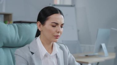 Ofiste bilgisayar başında çalışan, resmi giyinmiş esmer bir kadının görüntüsü. Korkunç baş ağrısından muzdarip hoş bir bayan. Yorgunluk, bitkin çalışma. Açık alan. İçeride, iş gününde.