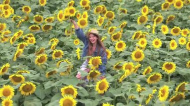 Komik kızıl adamın kızı boynundan tuttuğu, birlikte yürüdüğü ve ayçiçeği tarlasında çiçek topladığı güzel bir hava sahnesi. Romantik tatil. Yaz zamanı..