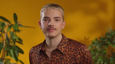 Mutlu yüz gay adam döner kameraya gülümseyen yeşil arka plandaki yeşil yapraklara bakar