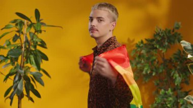 Gülümseyen adam omuzunda Lgbt bayrağı tutuyor şık gömlekler içinde kameraya bakıyor. Mutlu ol.