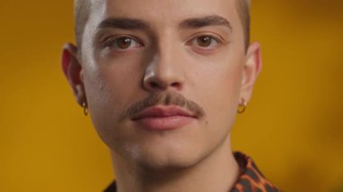 Çekici eşcinsel adamın stüdyo portresi sarı arka planda gülümseyen kameraya bakar