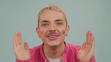 Mutlu gay adam kameraya bakıyor, gülümseyen yüzlerden el ele tutuşuyor. Boyalı gökkuşağı Lgbt bayrağı