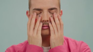 Genç eşcinsel adam kameraya bakar boyalı gökkuşağı Lgbt bayrağıyla el ele tutuşur