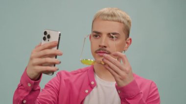 Portre gülümseyen adam stüdyoda güneş gözlükleriyle selfie çekiyor. LGBT. Pozisyon