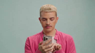 Mutlu gülümseyen adam kameraya telefonla bakar. LGBT. Telefonu parmağıyla gösteriyor.