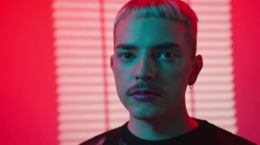 Adamın portresi pembe arka plandaki kameraya ciddi bir şekilde bakıyor. Lgbt