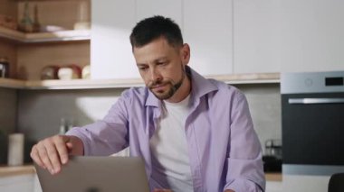 Dizüstü bilgisayarda çalışırken başı ağrıyan, kafasına dokunan genç ve yorgun bir adamın fotoğrafı. Yakışıklı işçi fazla çalışmaktan yorgun düşmüş. Evden uzakta çalışan bir adam.