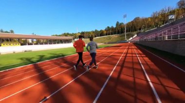 Spor sahasında birlikte koşan sportif koşucular ısınma egzersizleri yapıyorlar. Stadyum. İnsanları eğitmek. FPV konsepti.