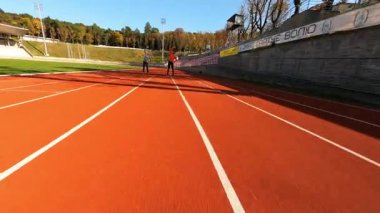 Profesyonel spor çifti stadyumda koşmadan önce kardiyo egzersizleri yaparken FPV görüntüsü. Aktif insanlar. Spor ve eğlence..