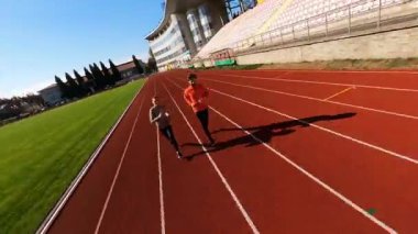 Dışarıdaki büyük futbol stadyumunda birlikte koşan aktif bir çiftin FPV görüntüsü. Spor takımı. Eğlence etkinliği. Sağlıklı yaşam tarzı.