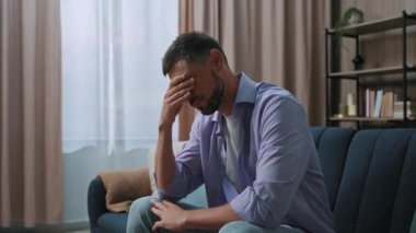 Evdeki kanepede oturan yakışıklı üzgün adam kendini stresli hissediyor. Yalnız adam. Modern daire. Yorgunluktan bunaldım. Yavaş çekim