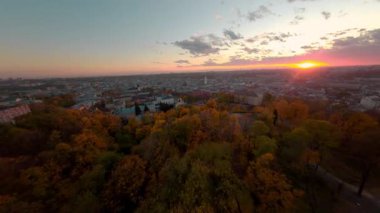 Manzara. Gün batımı şehri. Göz kamaştırıcı bir manzarada güzel bir FPV manevra kabiliyeti. Sinematik gökyüzü olan akşam manzarası. Hava görüntüsü.