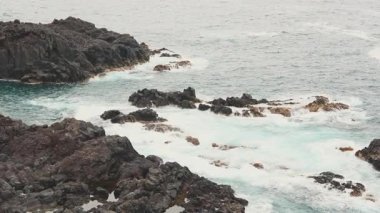 Kıyı şeridindeki sinematik ve keskin kayaların havadan görünüşü. Sahile çarpan dramatik dalgalarla güzel, fırtınalı okyanus..