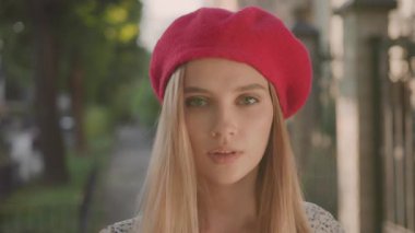 Kameraya gülümseyen kırmızı bereli, beyaz, sarışın bir kadının portresi. Sokak manzarası. Sunset Caddesi. Güzel insan..