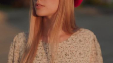 Beyaz, zarif, şık bereli bir kadın güneşli bir akşamda kameraya bakıyor. Dış portre. Dişiler. Güzellik ve moda.