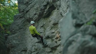 Profesyonel genç dağcı, parlak renkli giysiler içinde kayalıklara tırmanıyor. Dağcı. Dağcı.