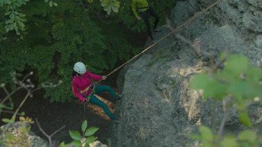 Kask takan, güvenlik halatlarıyla kayalara tırmanan genç bir kadını hava saldırısı ile vurdular. Uçuruma tırmanmak. Yürüyüş. Dağcı kız.