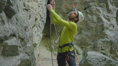 Beyaz saçlı yakışıklı dağcı tırmanma ekipmanlarını ayarlıyor uzun güvenlik ipleri etkinliğe hazırlanıyor. Profesyonel dağcı. Orman.
