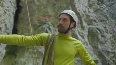 Genç sakallı adam ormanın derinliklerindeki kayalara tırmanıyor. Aktif yakışıklı adam ormanda tırmanıyor. Profesyonel ekipman.