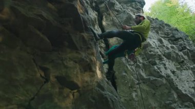 Genç sakallı adam dağ tırmanışından atlama ipi kullanıyor. Dağlarda aktif dağcı yürüyüşü. Orman doğası. Sıra dışı spor.