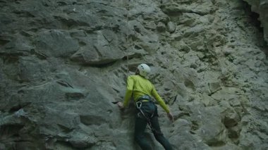 Genç sıska sporcu ormanda dağın tepesine tırmanıyor. Sakallı profesyonel dağcı dikkatlice kayaya tırmanıyor. Ekstrem sporlar. Yaz zamanı..