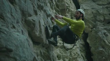 Aktif sakallı adam ormanda dağa tırmanıyor. Dar kesim dağcı genç sporcu kayalara tırmanıyor..