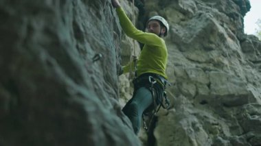 Formda, esnek, sakallı genç sporcu dağ kayası uçurumuna tek başına tırmanıyor. Profesyonel dağcı..