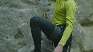 Dikkatli, sakallı, dağa tırmanan genç yürüyüşçüye yaklaşıyoruz. Kask takan dağcı güvenlik ekipmanı kullanarak kayayı tırmanmaya devam ediyor..