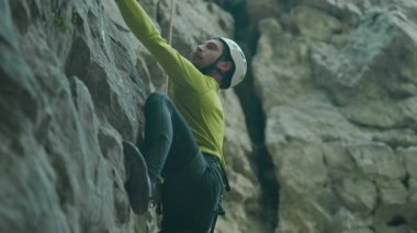 Formda sakallı genç sporcu sert kayalara tırmanıyor. Profesyonel dağcı güvenlik ekipmanlarıyla dağa tırmanır. Orman maceraları. Yürüyüş.