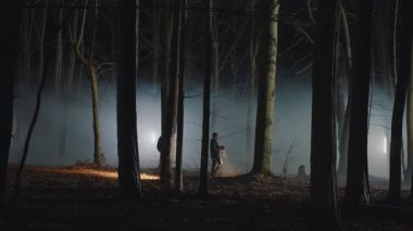 İki genç erkek dedektif gece vakti ormanda dolaşıp, ceset arıyorlar. El fenerlerini tutan ve etrafa bakan adamlar. Endişe, korku. Korku filmi