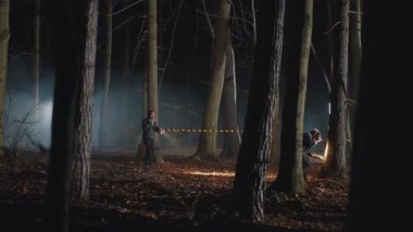 İki hippi geceleri boş ormanda dolaşıp etrafa bakınıyorlar. Genç dedektifler suç mahallinde çalışıyor, ellerinde fenerler var. Gölgeli adamlar. Yeşillik, sonbahar. Korku sahnesi. Polis kurdelesinin dikkatine.