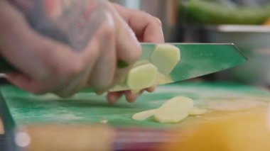 Şefin elleri taze zencefili dilimlerle kesiyor. Sağlıklı çay için bitki karışımı yapan bir adam. Boğaz ağrısı için iç. Restoran mutfağı, kapalı bir yer.