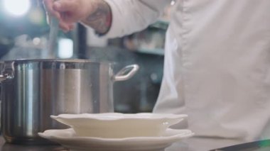 Restoran şefi kepçeyi elinde tutuyor, lezzetli çorba pişiriyor. Yemek vakti. Geleneksel Fransız yemekleri. Aşçı lokantanın mutfağında çalışıyor. Yemek, sağlıklı yemek, mutfak, yemek tarifi.