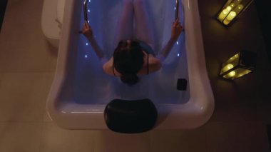 Spa kliniğinde jakuzideki çekici bir kadın. Sağlığa önem ver. Vücut dinlenmesi. Rahatlatıcı eğlence zamanı. Karanlık odada. Mavi ışık. Yavaş çekim