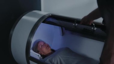 Yakın plan kadın, özel makinede yatıyor. Adam kapıları kapatıyor. Kozmetoloji prosedür kavramı. Kilo kaybı. Vücut bakımı. Yavaş çekim