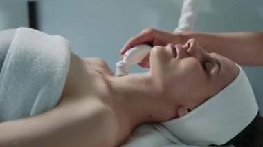 Güzellik salonunda kaldırma prosedürü uygulayan hoş bir genç bayan. Deneyimli kozmetik uzmanı müşteriyle çalışıyor, boyuna dokunuyor ve özel aletler kullanıyor. Sağlık hizmeti, cihaz. Sabırlı, gevşemiş, sağlıklı.