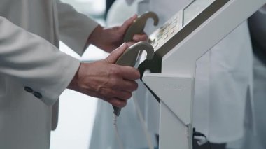 Yaşlı beyaz bir kadının eğitim aletlerini elleri için kullanmasının görüntüleri. Rehabilitasyon konsepti. Spor. Antrenmandaki emekli kadın. Sağlık hizmetleri. Tıbbi ekipman