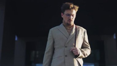 Şık bir şehirli adam, hareketli bir modern şehir ortamında, gerçek şehir zarafetini somutlaştırarak rahatça yürür.