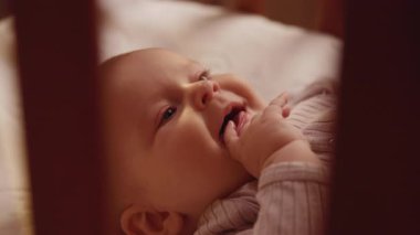 Çocuk beşiğinin arkasında yatıp etrafa bakarken yeni doğmuş şirin bir bebeğin gülümseyen yüzü. Komik, şakacı çocuk. Kapatın. Yavaş çekim