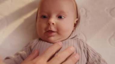 Bebek beşiğinde sırt üstü uzanmış, gülümseyen küçük bebeği kapat ve baba okşarken ellerini kaldır. Portre sanatçısı çocuk. Kapatın. Yavaş çekim