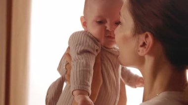 Sevimli, genç, mutlu anne kucağında ve yeni doğmuş bebeği okşuyor. Gülümsüyor. Apartmanda dikiliyorum. Annelik. Portre. Yavaş çekim