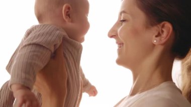 Bir annenin bebeğine sevgiyle gülümsediği, sevgisini ve bağlantısını yakaladığı yürek ısıtan ve güzel bir sahne.