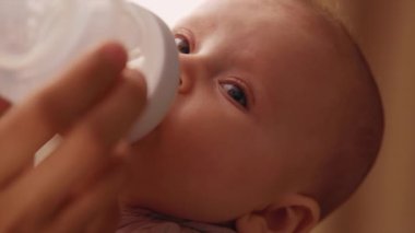 Birlikte güzel, huzurlu bir anda bir şişeden rahatça beslenen bir bebeğin hoş bir yakın çekimi.