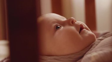 Babaya bakan tatlı bir erkek bebek. Erkek eli, tahta beşikte uzanmış gülümseyen güzel çocuğun burnuna dokunuyor. İçeride. - Eve. Dikkat, şefkat