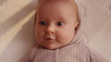 Komik bebeğin yukarıdan görünüşü şaşırttı. Beyaz, tatlı bir oğlanın yakın çekim görüntüleri. Bebek evdeki beşik yatağında dinleniyor. Annelik ve çocuk kavramı. Ev