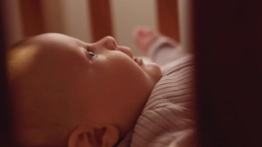 Beşikte yatan mutlu kızı vurmak. Olumlu duygular. Ebeveynler. Evdeki yatakta beyaz bir bebeğin portresi. Oturma odası. Şirin bebek yüzünün yakın çekimi.