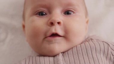 Yeni doğmuş şirin bebeğin portre yüzü gülümsüyor, beşikte sırtüstü yatıp etrafa bakıyor. Komik, şakacı çocuk. Kapatın. Yavaş çekim