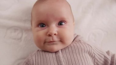 Sevimli, komik, yeni doğmuş bebek gülümseyen, çocuk beşiğinde sırtüstü yatıp etrafa bakan. Portre sanatçısı çocuk. Kapatın. Yavaş çekim